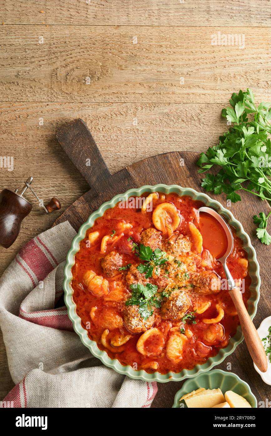 Soup. Fresh tomato soup with meatballs, pasta, vegetables and parsley in green rustic bowl on wooden background. Traditional Italian cuisine. Healthy Stock Photo