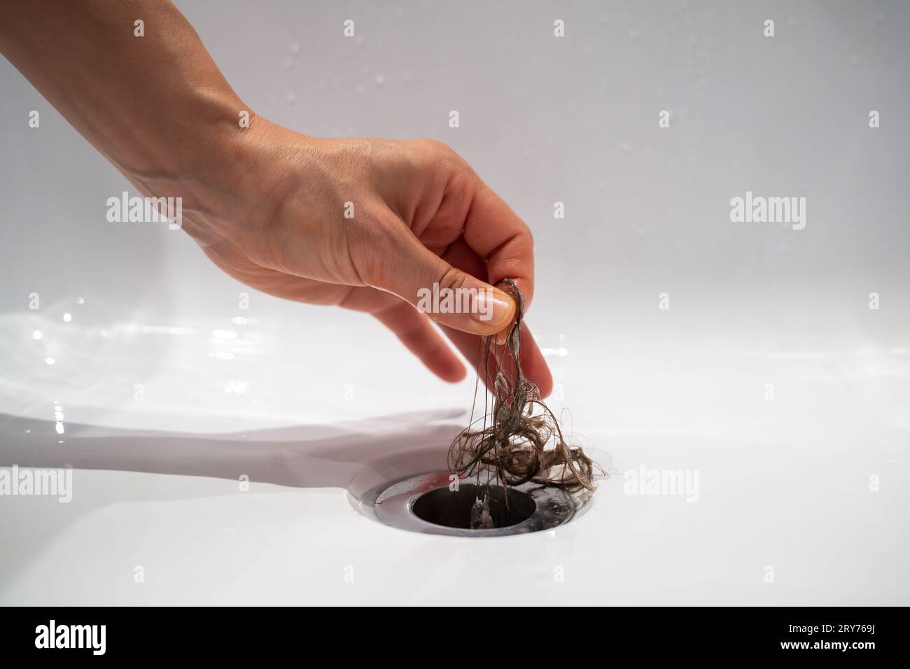 Water drain hole in bath is clogged with hair clump in bathroom at home