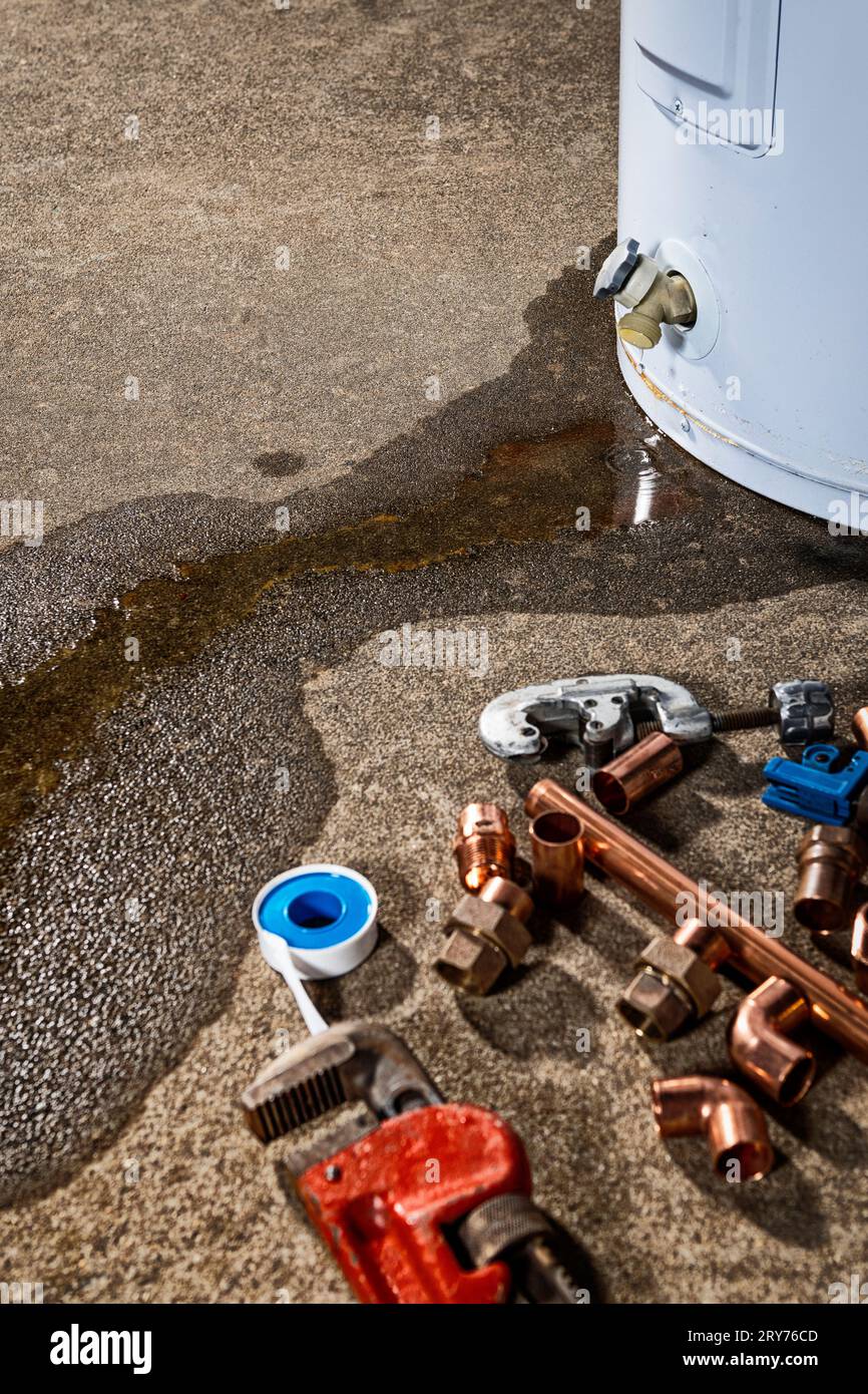 Water leaking from the plastic faucet on a residential electric water heater with tools to