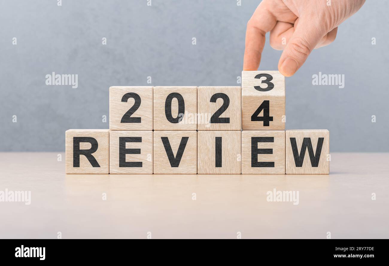 Review 2024. hand flips wooden cube and changes words REVIEW 2023 to