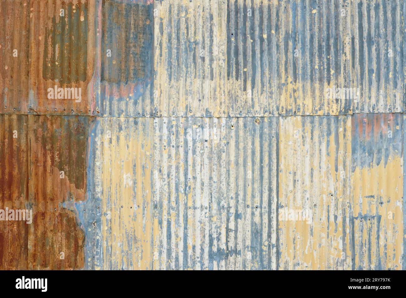 A rustic looking corrugated metal wall with patterns of colour. Stock Photo