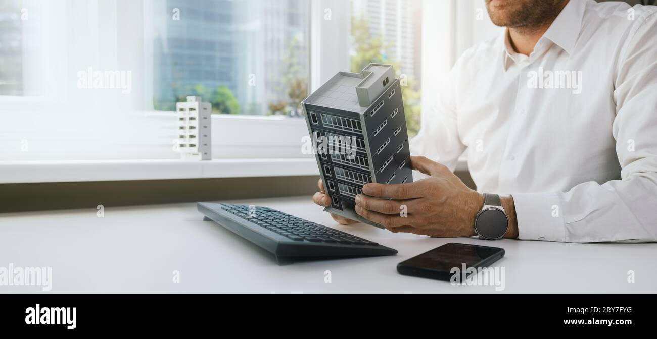 real estate business and development. businessman, developer or architect working in office, scale model in hands. new apartment building project. ban Stock Photo
