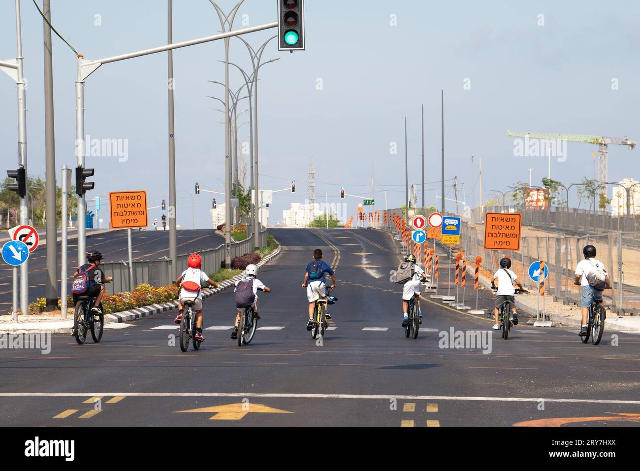 Rishon Lezion, Israel - September 25, 2023: Kids ride on bicycles along a highway empty of cars during the holiday of Yom Kippur Stock Photo