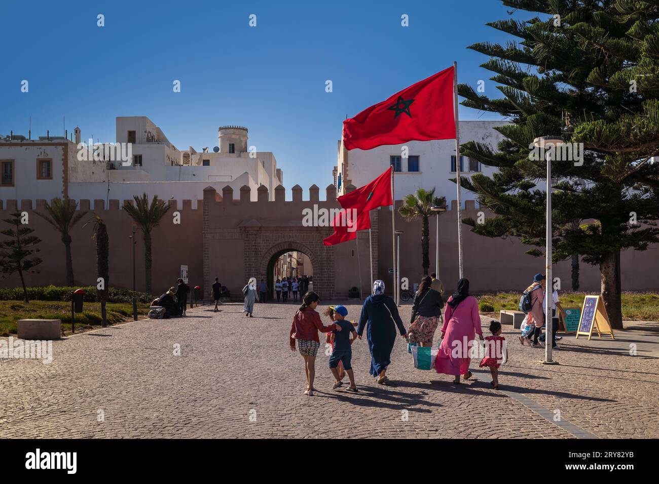 Essaouira, Morocco - August 3, 2023: A family is preparing to reach one of the access gates to the historic center of the town, among the waving Moroc Stock Photo