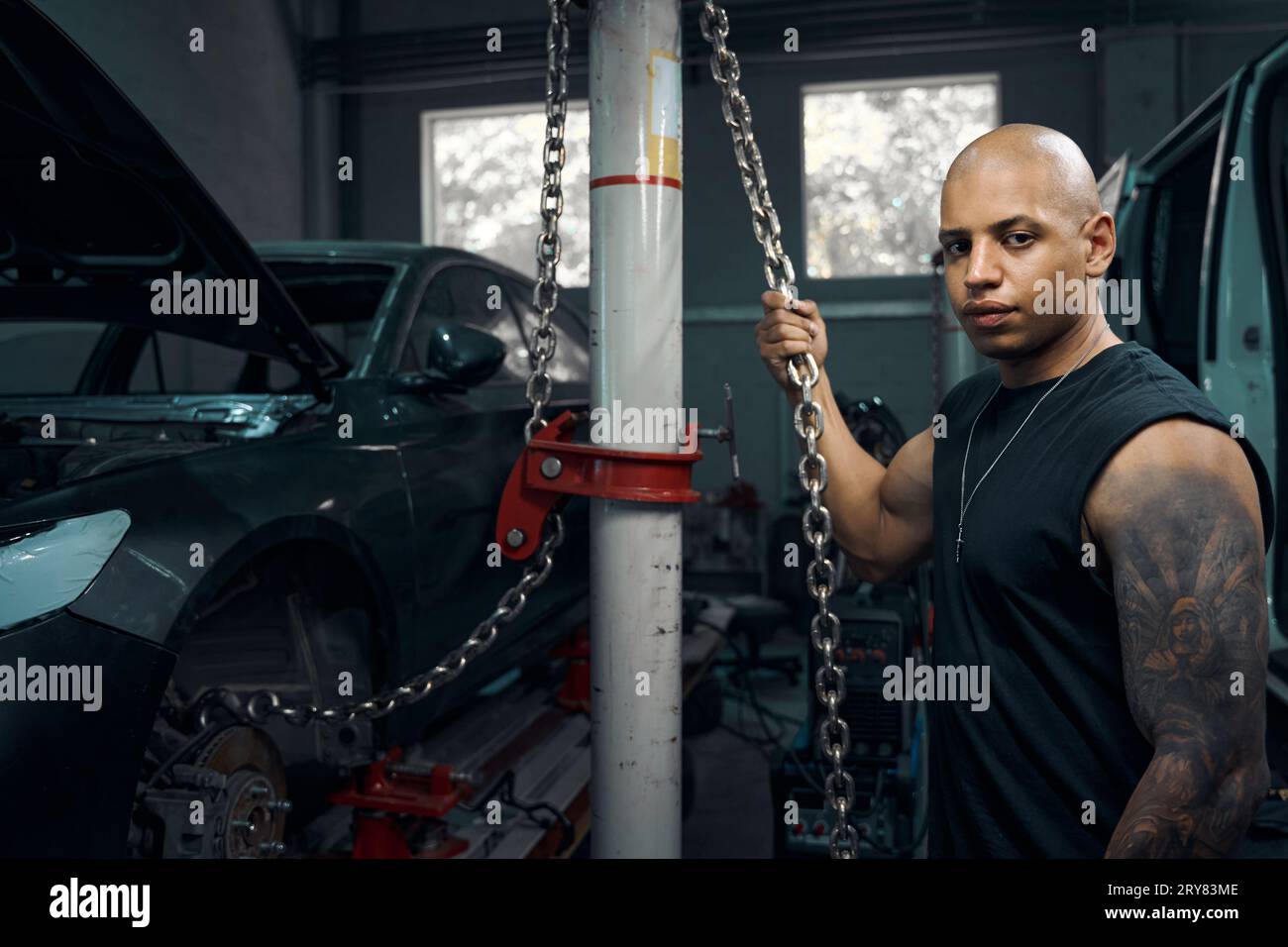 Auto mechanic holding chains that used to raise and lower motor vehicle Stock Photo