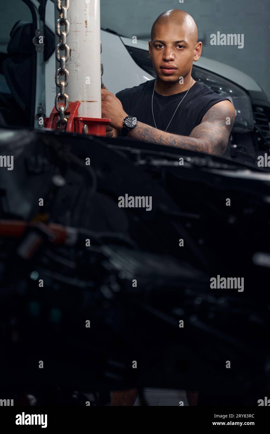 African American man securing chains that used to raise and lower cars Stock Photo