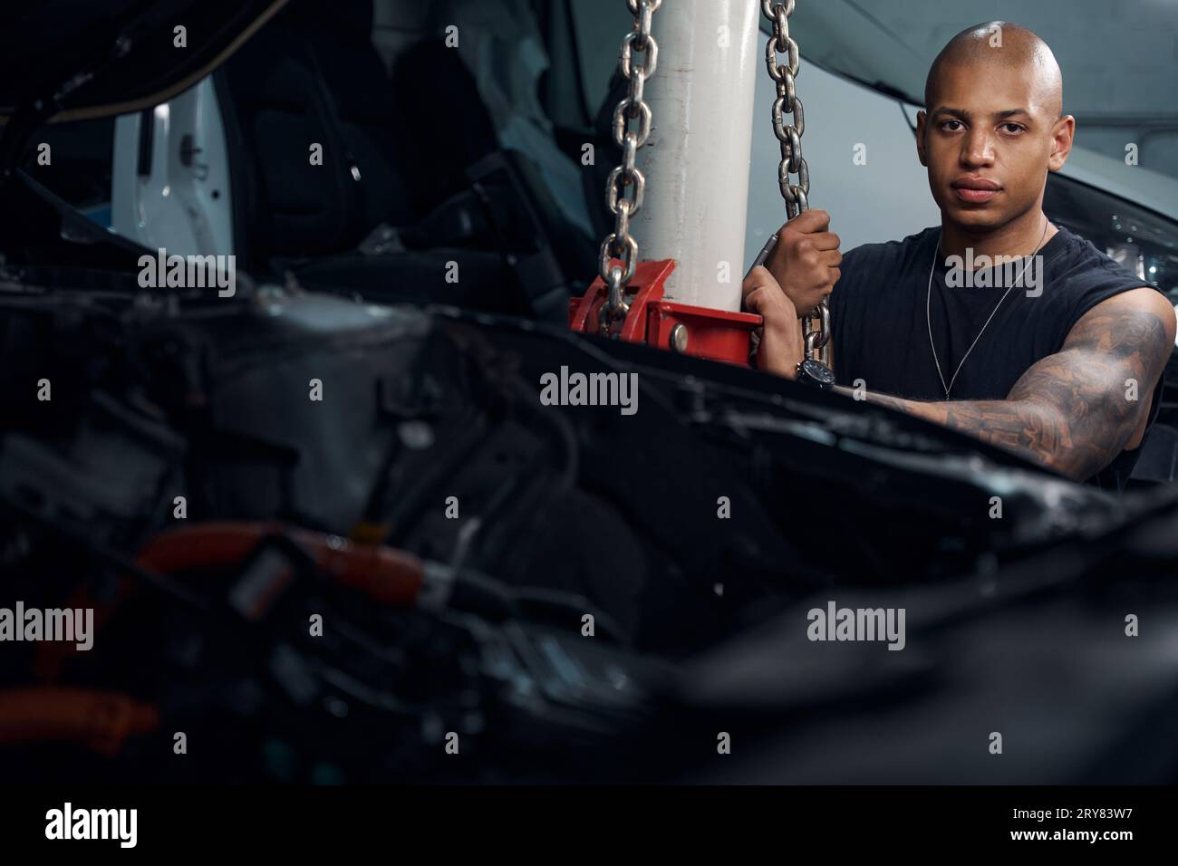 Repairman securing chains after raising automobile to required height Stock Photo