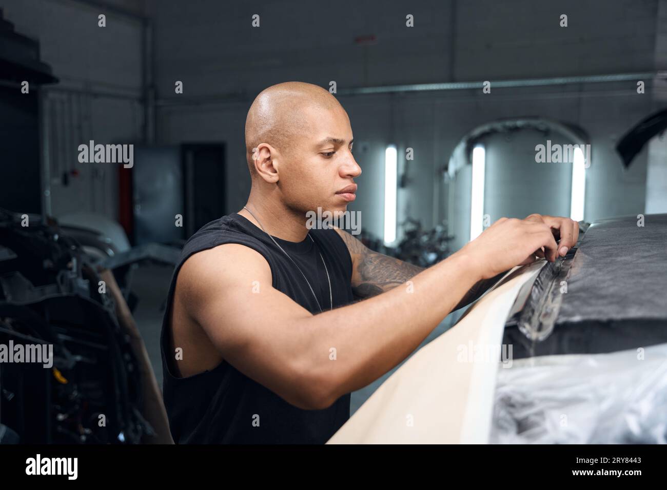 African American auto-repair shop worker preparing vehicle to repainting Stock Photo