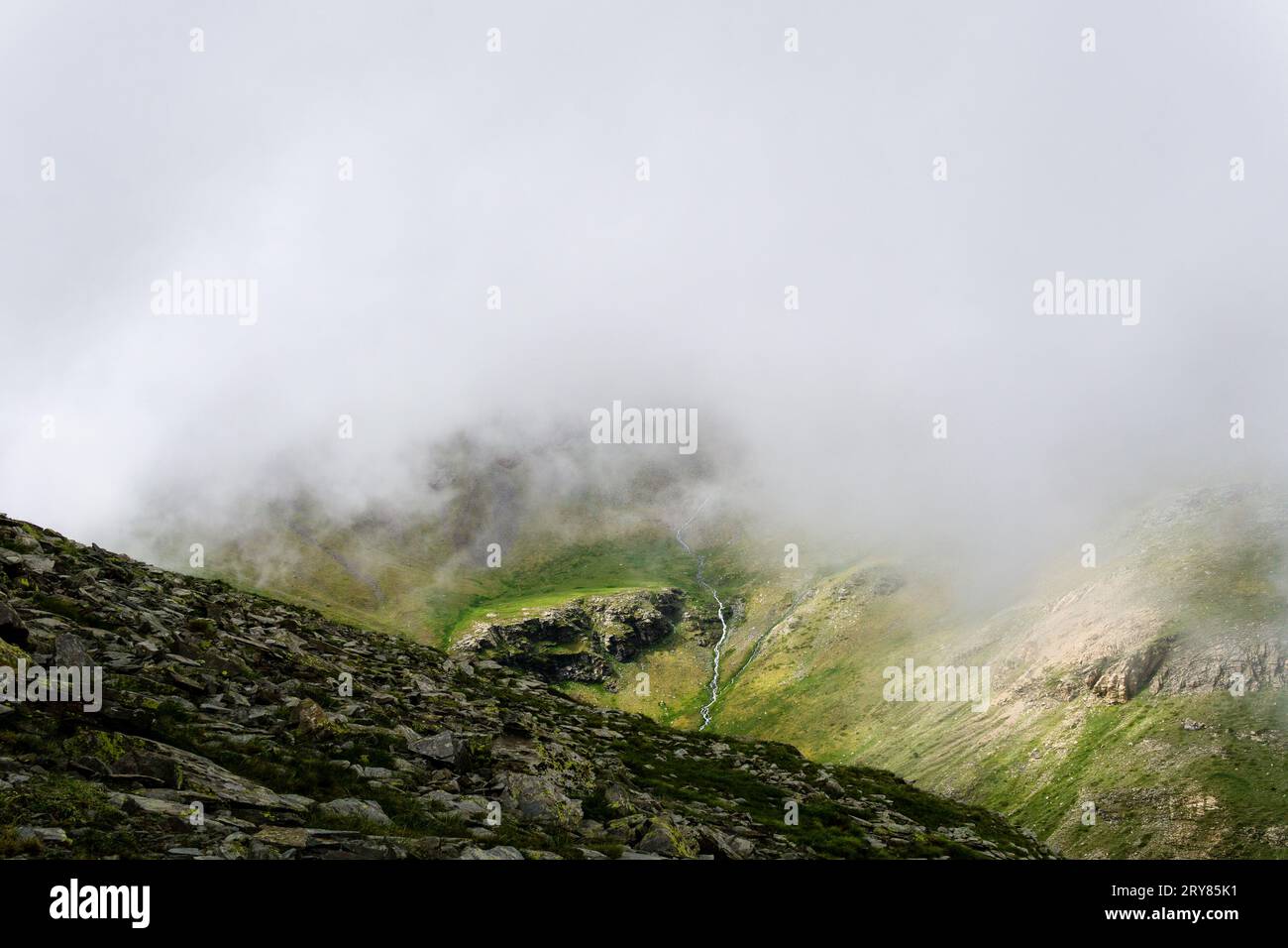 Running waterfall on a cloudy valley in Vall de Nuria Stock Photo