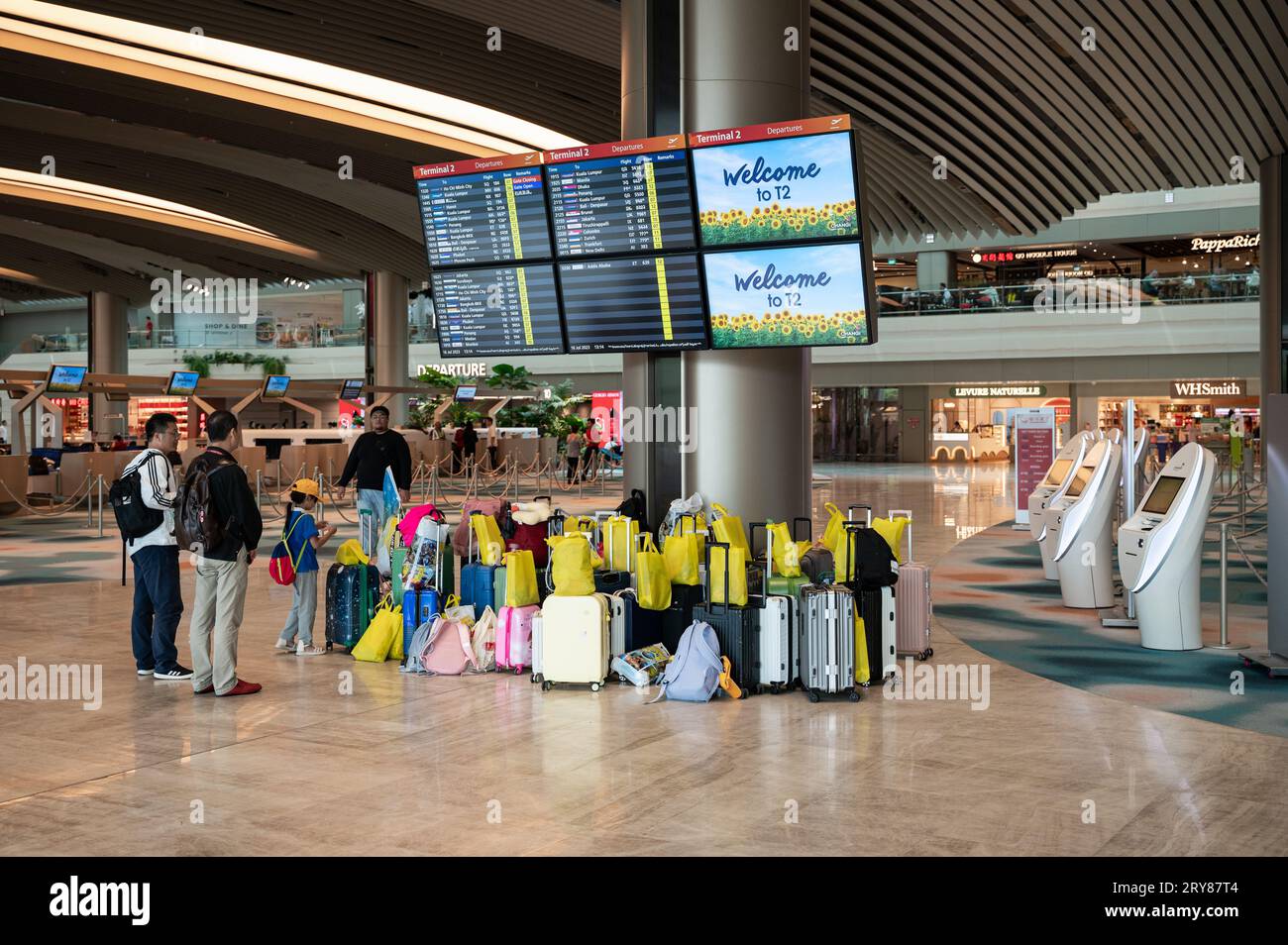 16.07.2023, Singapore, Republic of Singapore, Asia - Air travellers stand in front of flight information screens in the refurbished T2 departure hall. Stock Photo