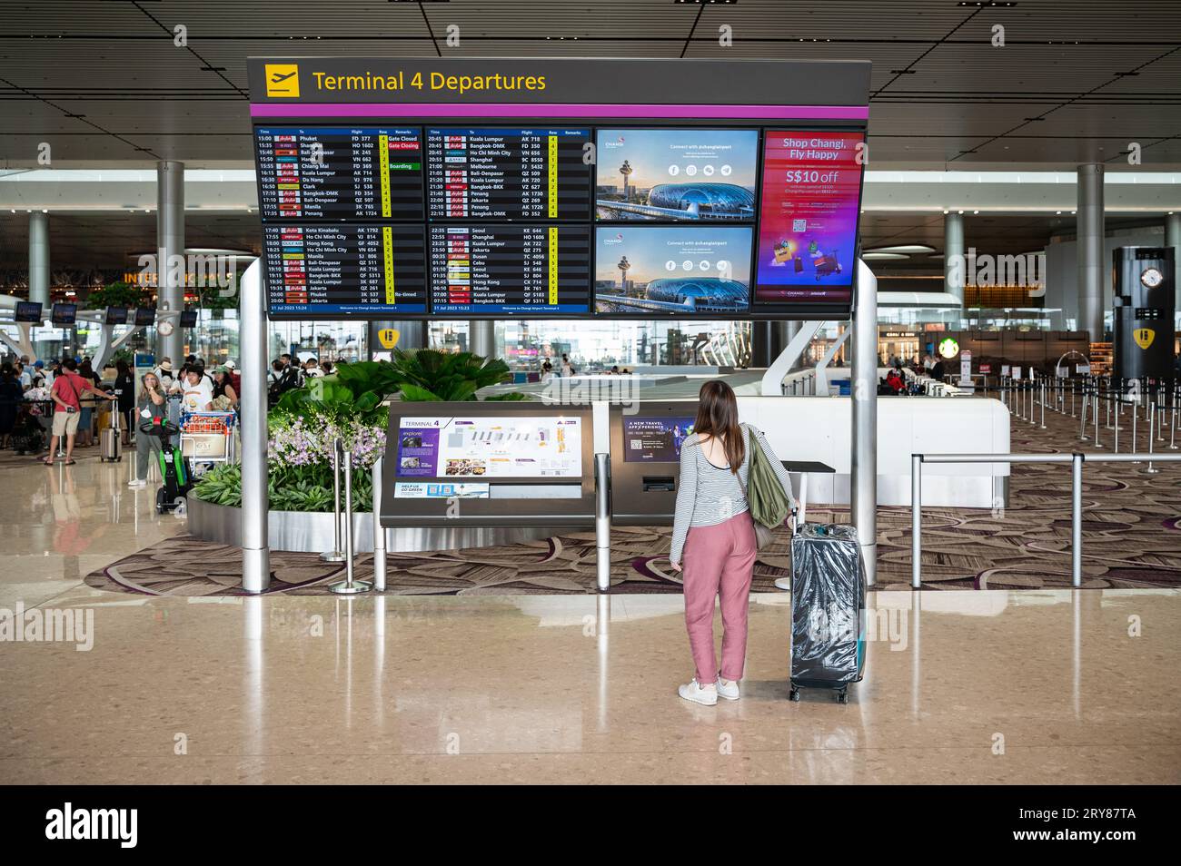31.07.2023, Singapore, Republic of Singapore, Asia - Air traveller stands in front of flight information screens in the departure hall at Changi's T4. Stock Photo