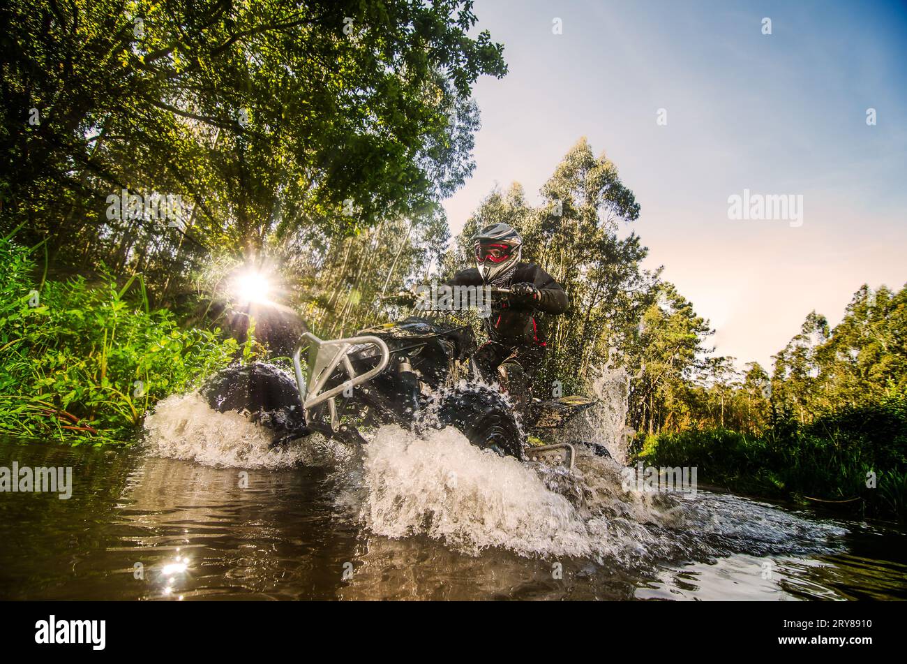 Quad rider through water stream Stock Photo - Alamy