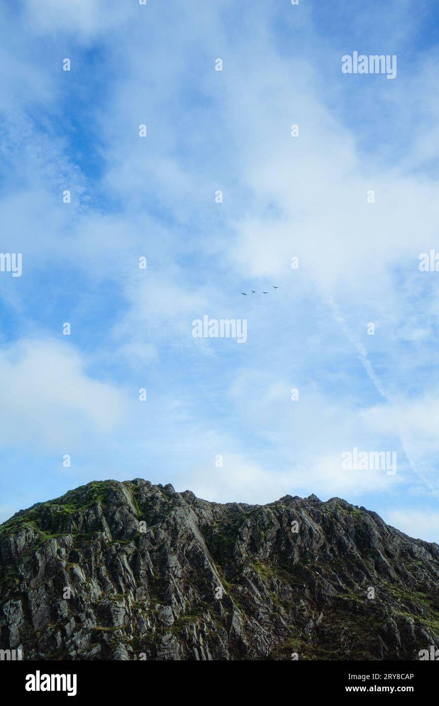 View of mountain peak against sky with birds in Lake District Stock Photo