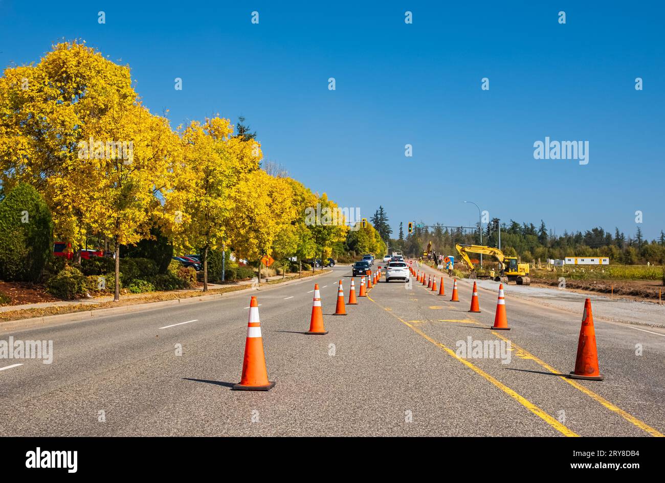 Orange cones set up to direct traffic. Construction site is repairing asphalt road pavement,road construction workers and road construction machinery. Stock Photo