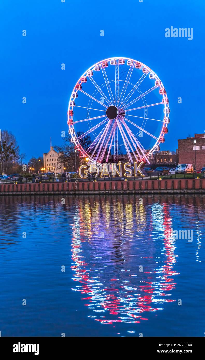 Colorful Ferris Wheel Illuminated Night Sign Inner Harbor Port Motlawa River Historic Old Town of Gdansk Poland. City formerly known as Danzig. Stock Photo
