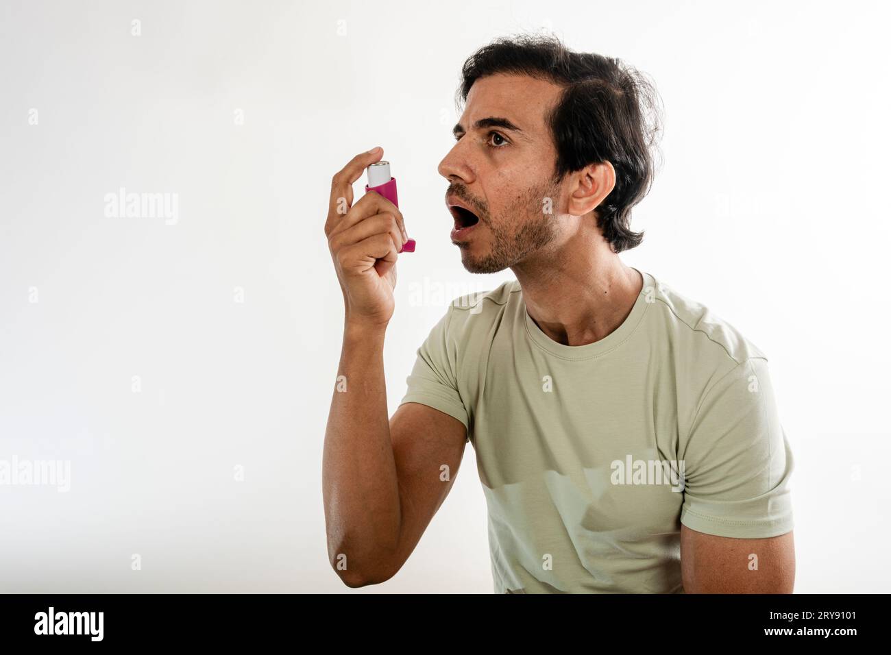 Asian young man from india using a respiratory inhaler. Study shot on white background, selective focus. Stock Photo