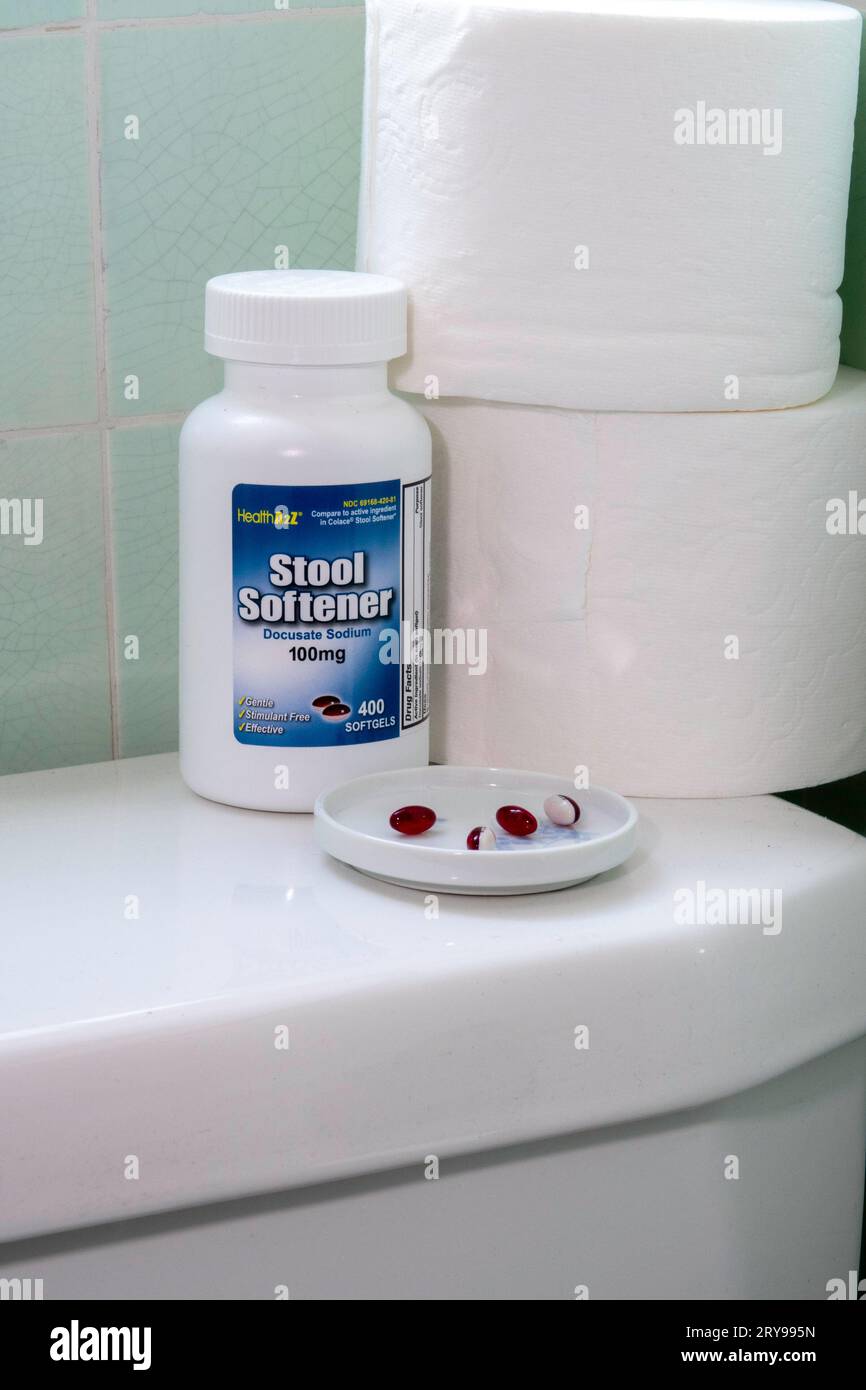 Still life of a bottle of stool softener, pills, and toilet paper rolls on top of a residential toilet, 2023, United States Stock Photo