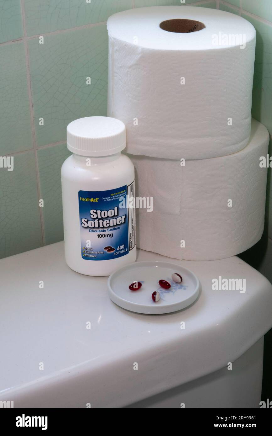 Still life of a bottle of stool softener, pills, and toilet paper rolls on top of a residential toilet, 2023, United States Stock Photo