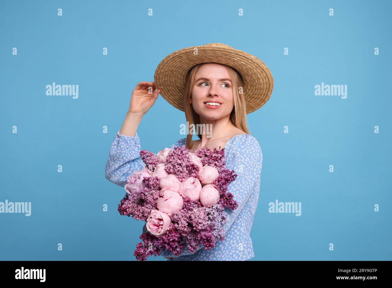 Beautiful woman with bouquet of spring flowers on light blue background ...