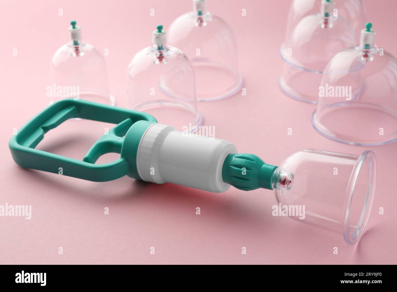 Plastic cups and hand pump on pink background. Cupping therapy Stock