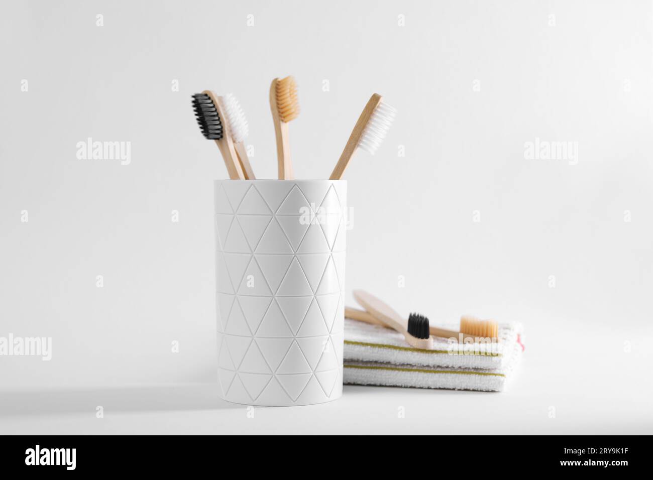 Bamboo toothbrushes in holder and towel on white background Stock Photo ...