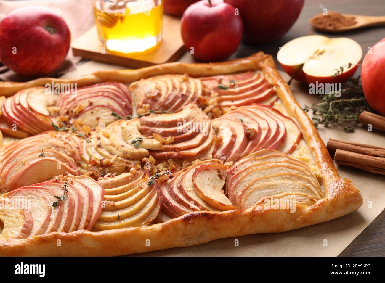Freshly baked apple pie with nuts and ingredients on wooden table, closeup Stock Photo