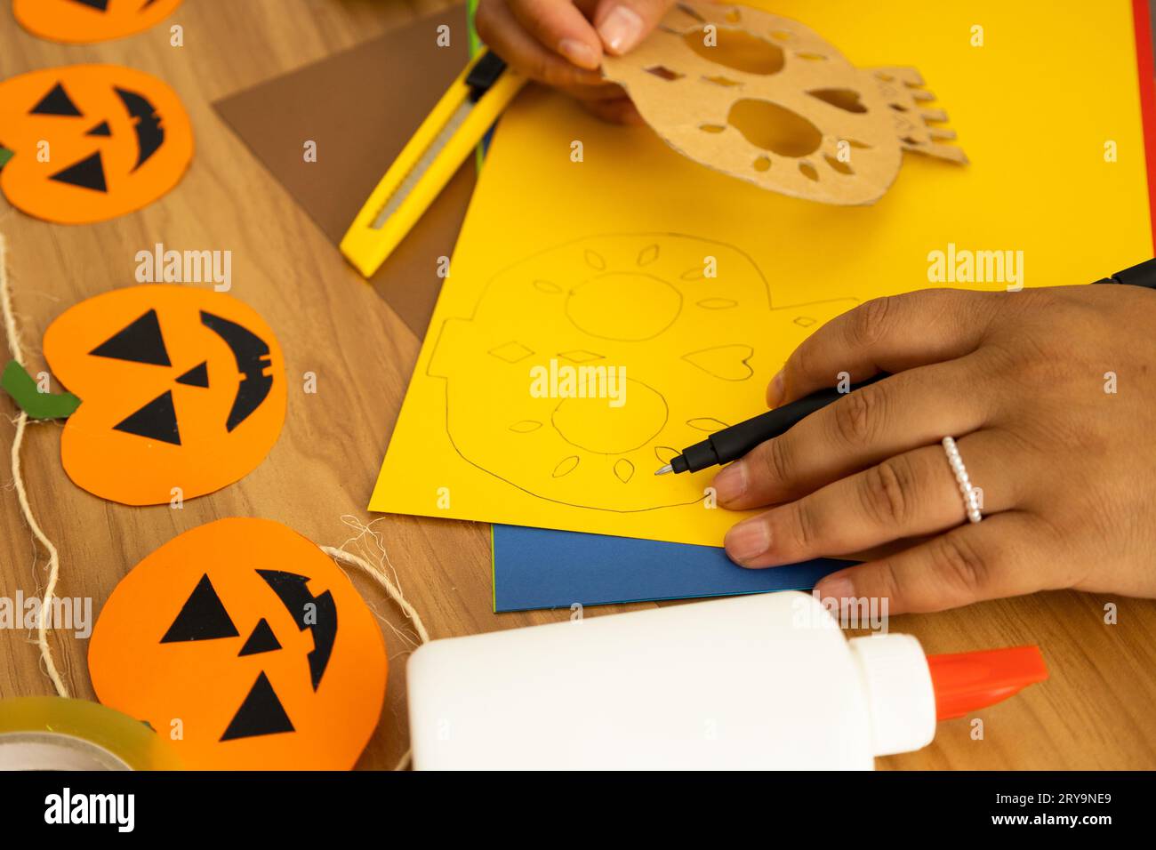 woman's hands holding a pen and in her other hand holding a mold to make a drawing of a day of the dead skull Stock Photo