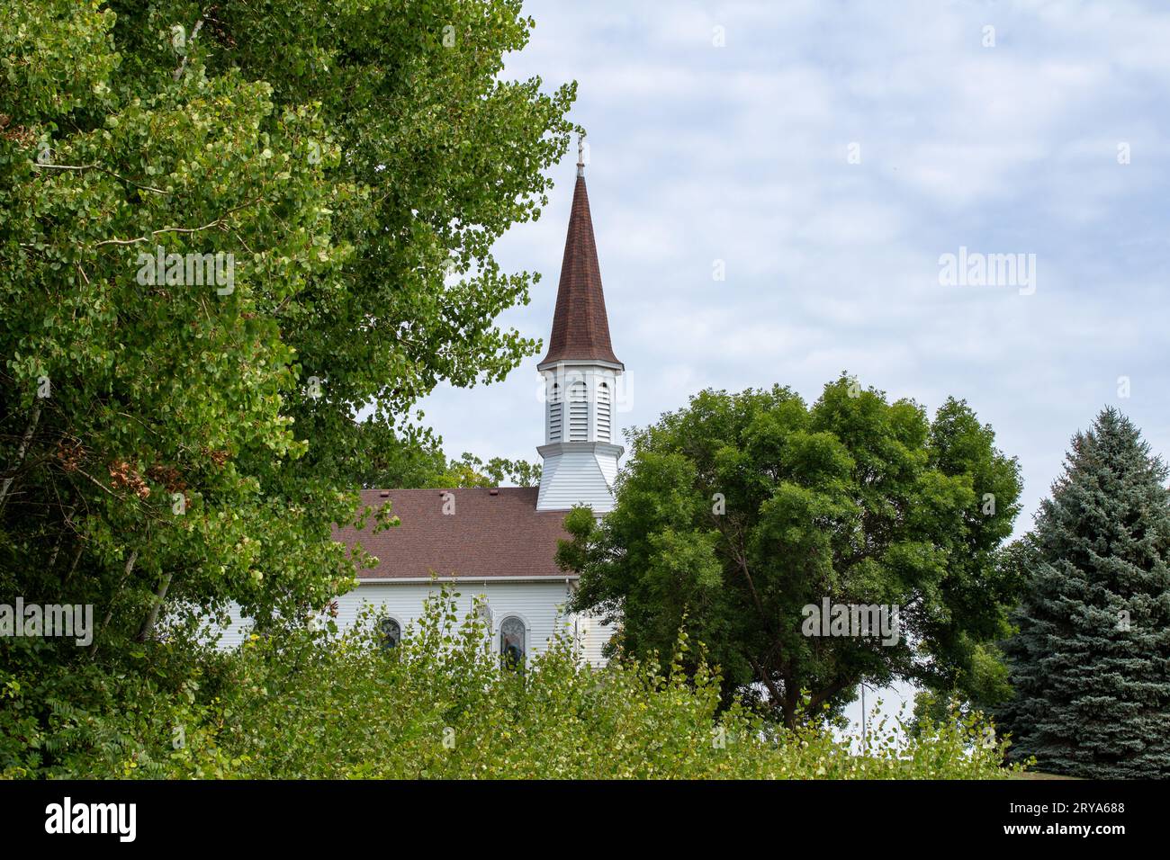 Landscape view of a picturesque old white wooden country church on a rural hillside Stock Photo