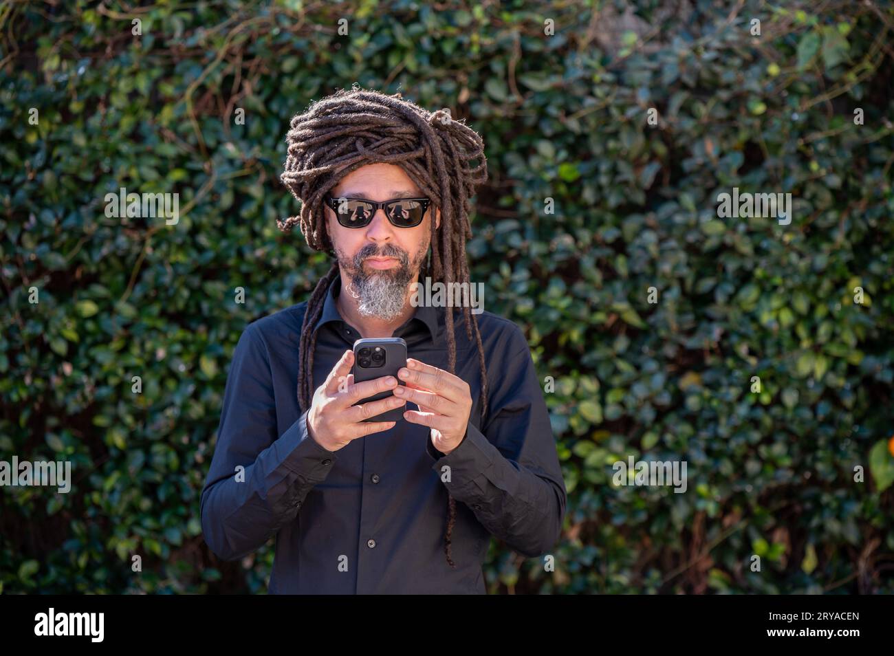 Man with locs hairstyle using his phone Stock Photo