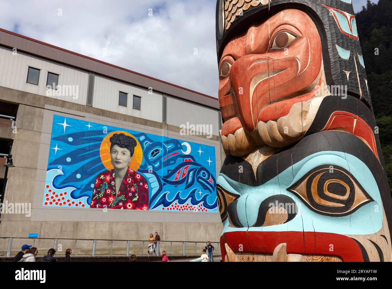 The Kaagwaantaan pole with the Elizabeth Peratrovich mural (by Crystal Worl) in the background. Downtown Juneau, Alaska, USA Stock Photo
