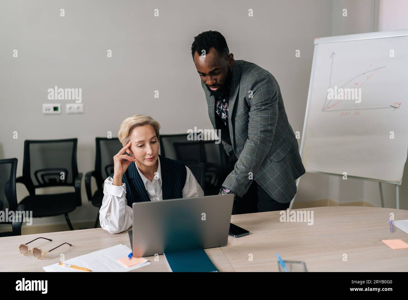 Portrait of helpful middle-aged female mentor teaching African-American intern student, talk instruct, help young trainee with computer work. Stock Photo