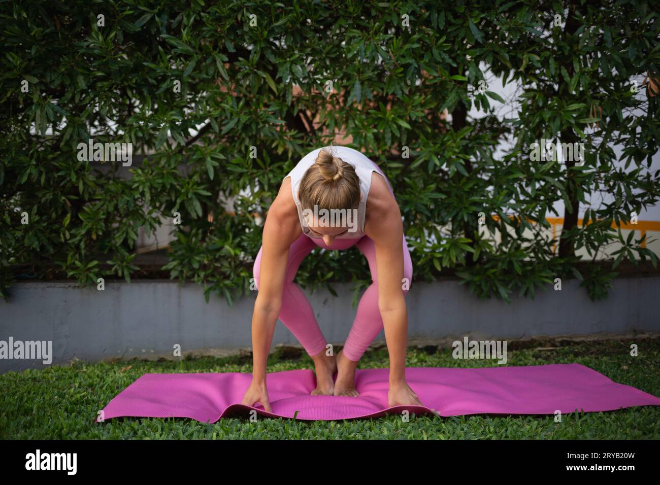 young beautiful pregnant woman practices yoga asanas on the green lawn outdoors. mindfulness and healthy lifestyle concept Stock Photo
