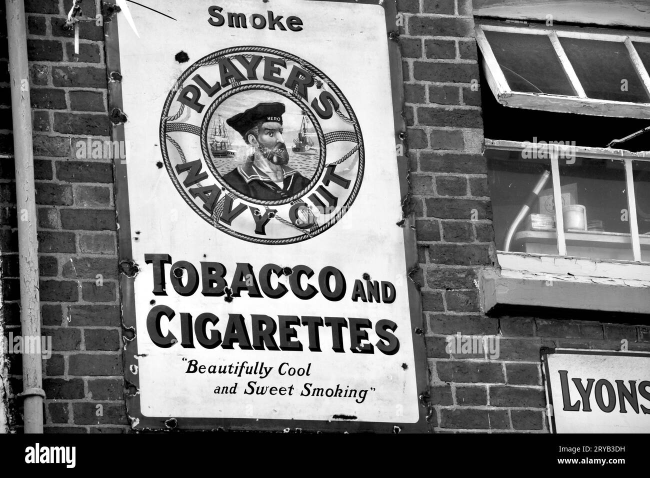 A black and white photograph of a vintage metal sign advertising