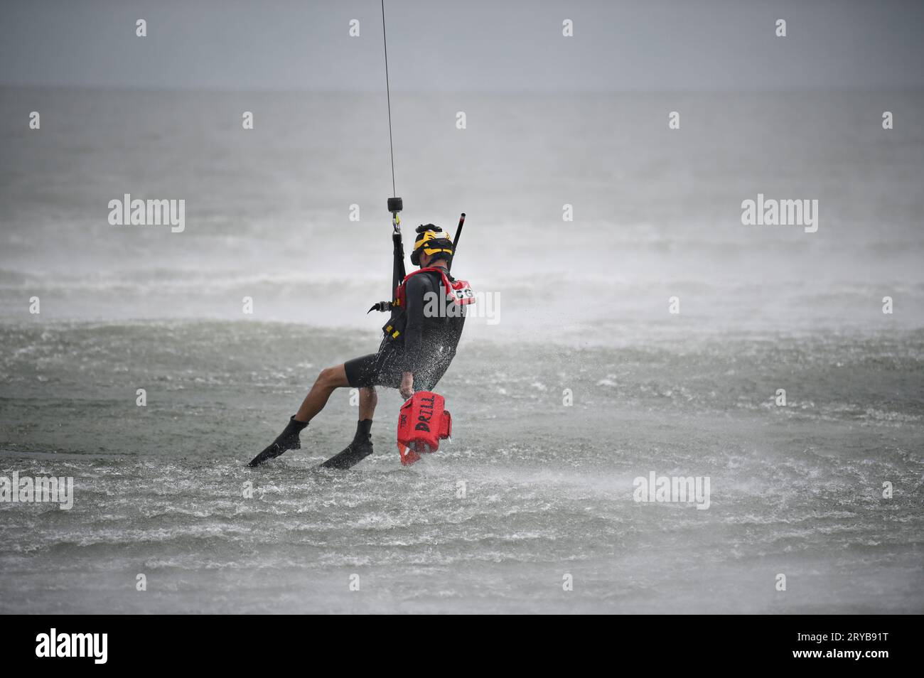 Milford Haven, United States. 30 August, 2023. A U.S Coast Guard Aviation Survival Technician retrieves a training buoy while suspended from a hoist line dangling from a helicopter during hoisting training on the Chesapeake Bay, August 30, 2023 near Milford Haven, Virginia. Credit: PO2 Ryan Noel/U.S. Coast Guard/Alamy Live News Stock Photo