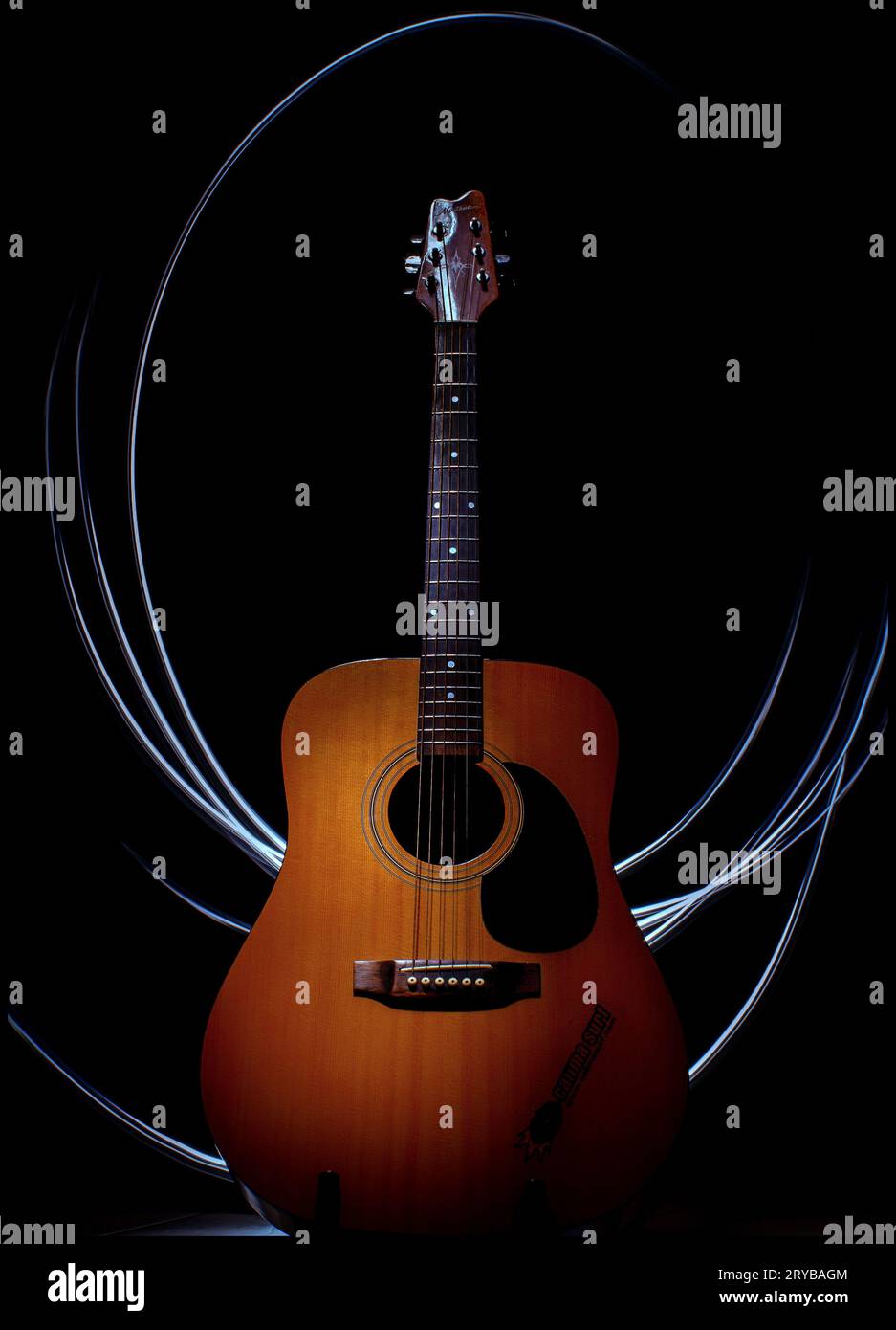 Acoustic guitar with light beams behind it on a black background Stock Photo