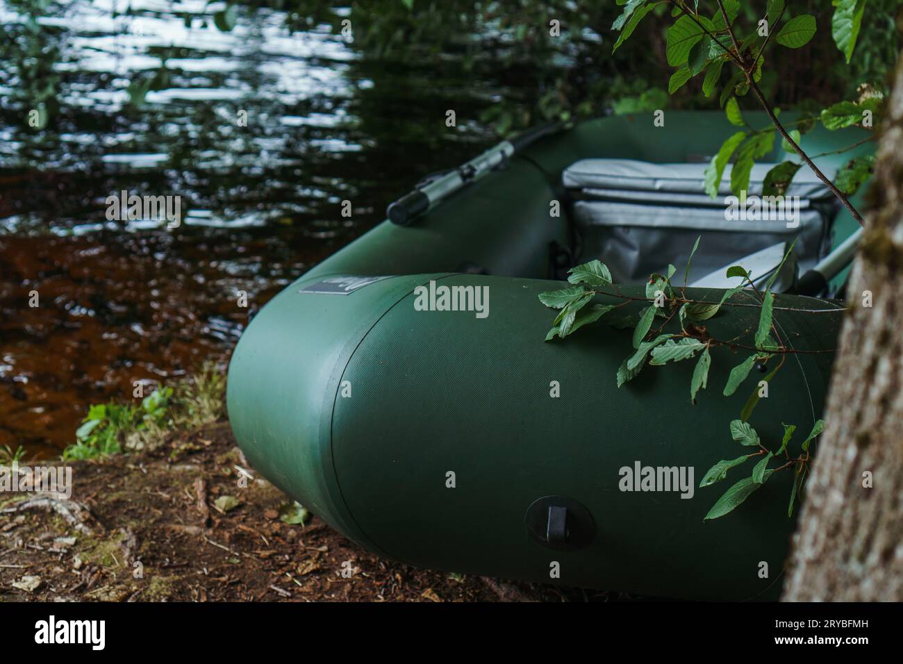 Modern green inflatable boat parked on shore near lake in evening ...
