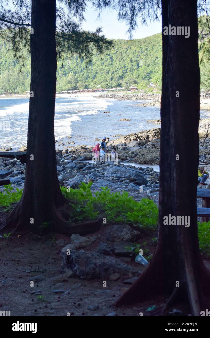Aceh, Indonesia - September, 2023: Unidentified people at the beach and Rocks on the beach in the evening Stock Photo