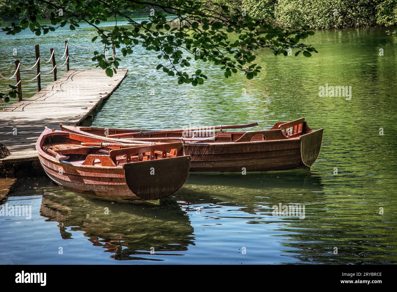 Rowboats sit quietly on a calm lake in Plitvice National Park, Croatia. Stock Photo