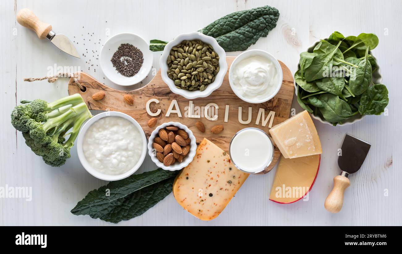 Foods high in calcium on and around a wooden board with the word calcium. Stock Photo
