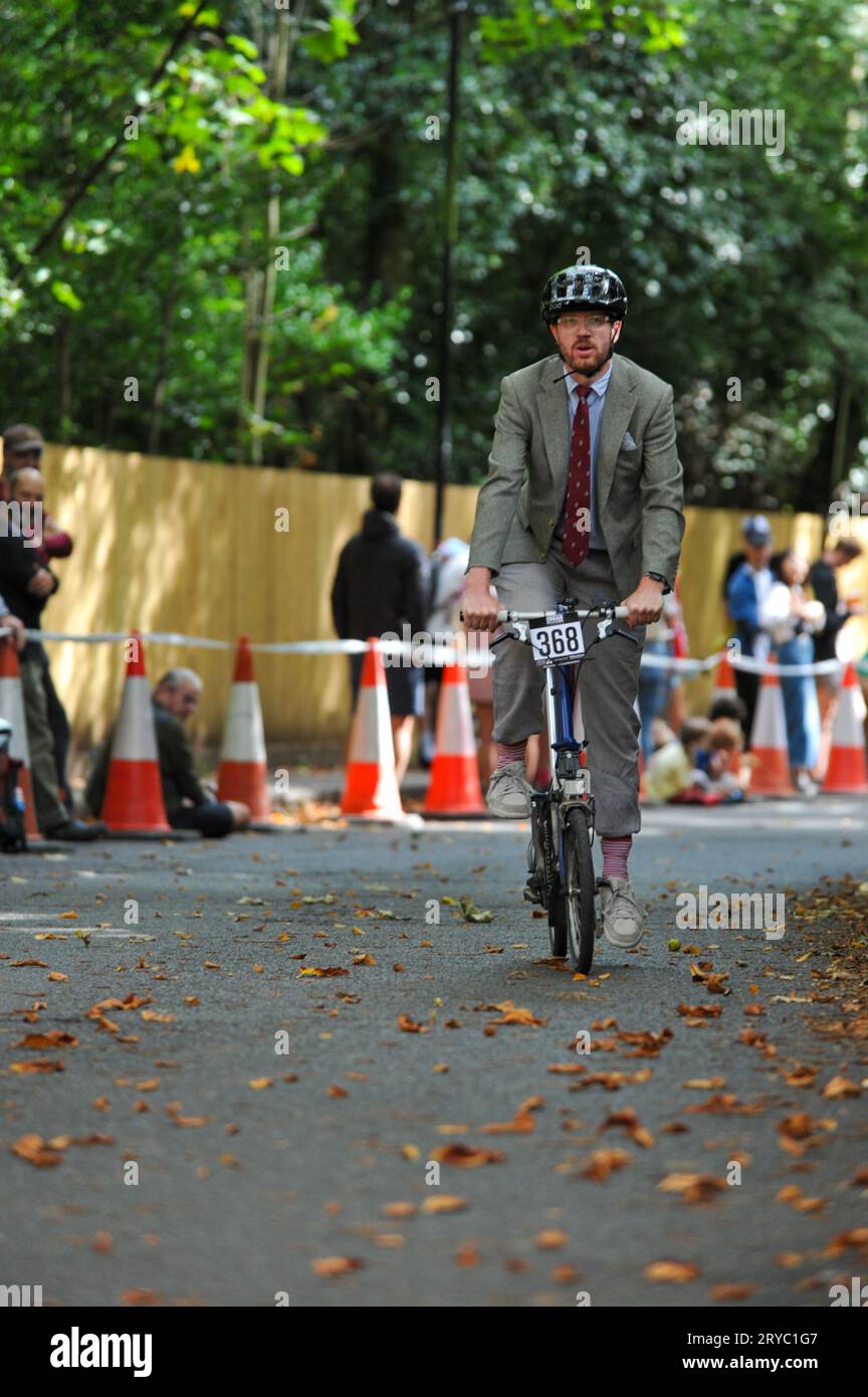 A cyclist, riding a Brompton folding bicycle, straining during the