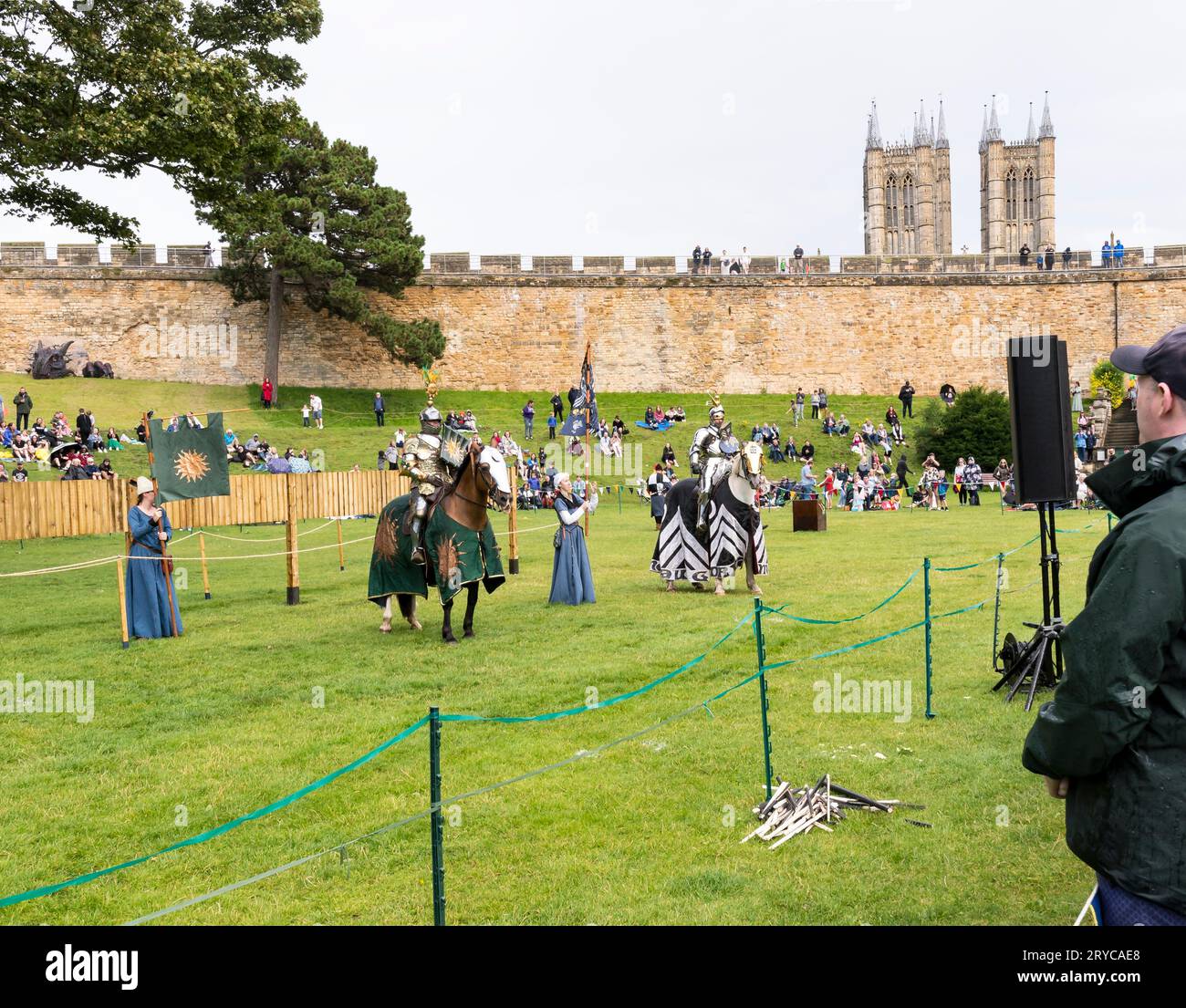 Two jousting knights on horseback with helpers holding banners taking audience applause, Lincoln castle, Lincoln City, Lincolnshire, England, UK Stock Photo