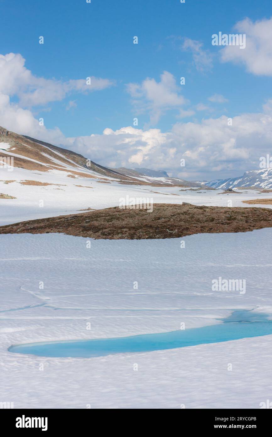 Snowy mountain landscape with blue ice water in the front on a sunny day Stock Photo