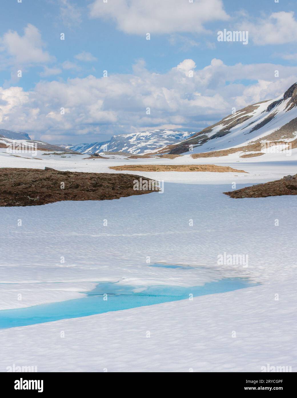 Snowy mountain landscape with blue ice water in the front on a sunny day Stock Photo