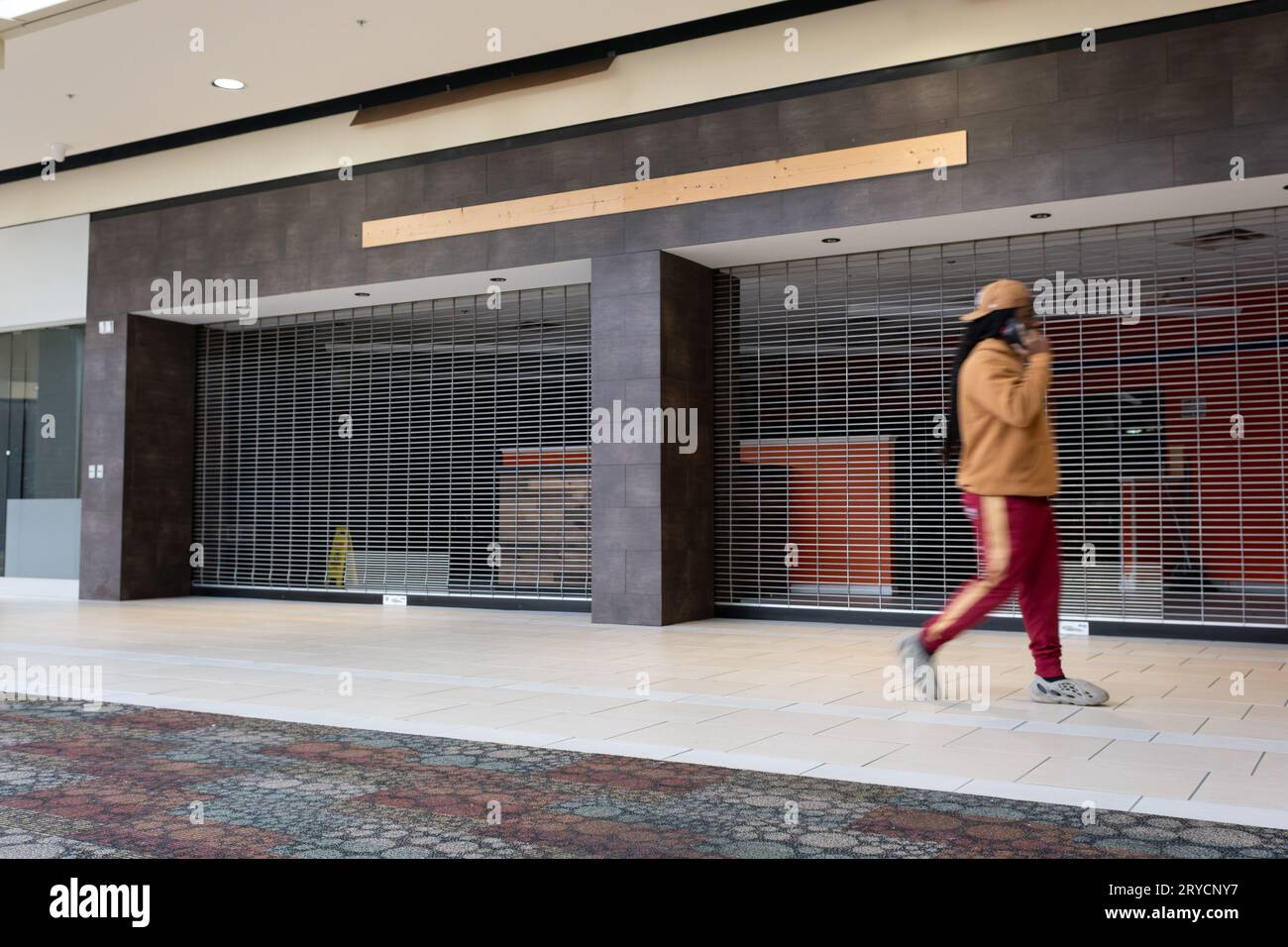 Young man walking past closed stores at the Genesee Valley Center mall