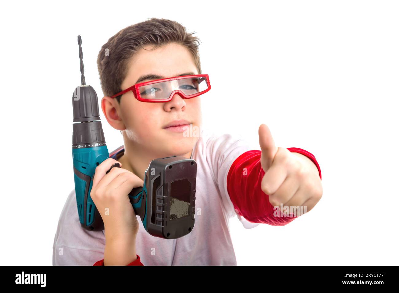 Boy wearing red goggles and holding a cordless drill makes success sign Stock Photo