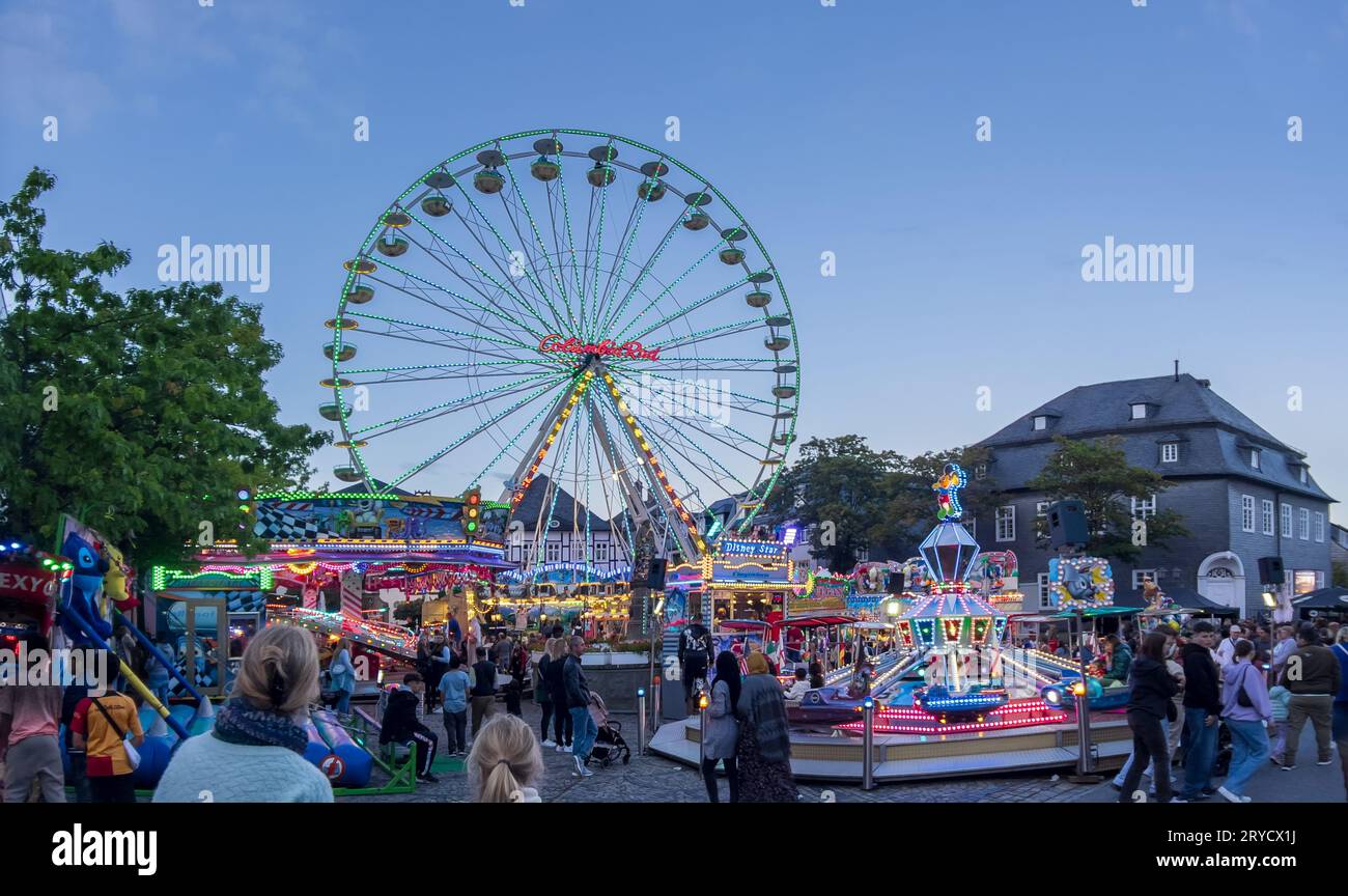 Brilon, North Rhine Westphalia - September 23rd, 2023: Illuminated Ferris wheel and children's carousel in the afternoon at the Brilon funfair. Unknow Stock Photo