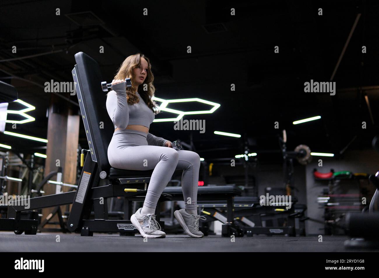 young girl in a gray tracksuit gymsuit In a dark gym, dissolve hair ...