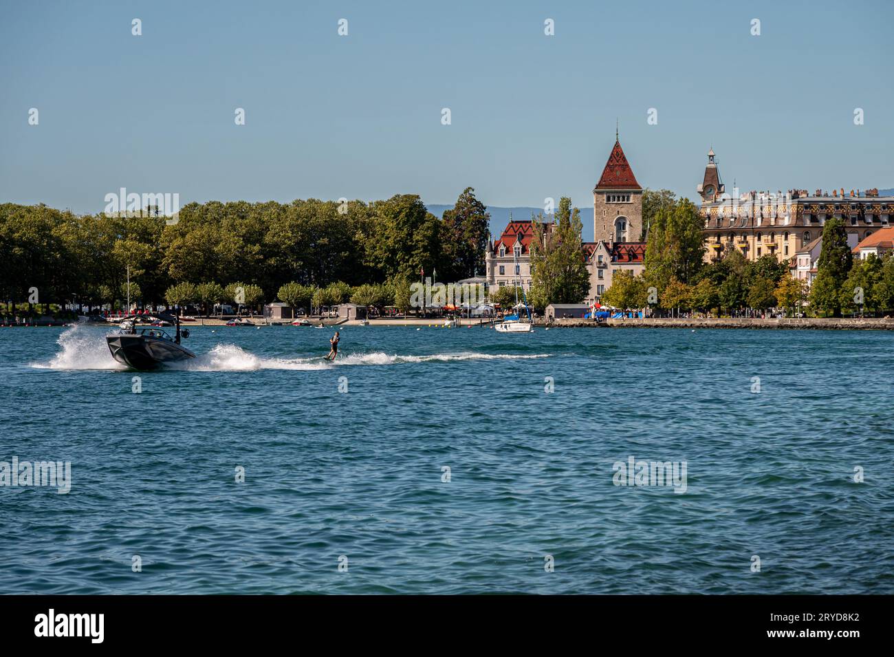 Ouchy, Lausanne, Vaud Canton, Switzerland - September 24, 2023 : Motorboat with people wakeboarding. Lake Geneva and Castle of Ouchy. Stock Photo
