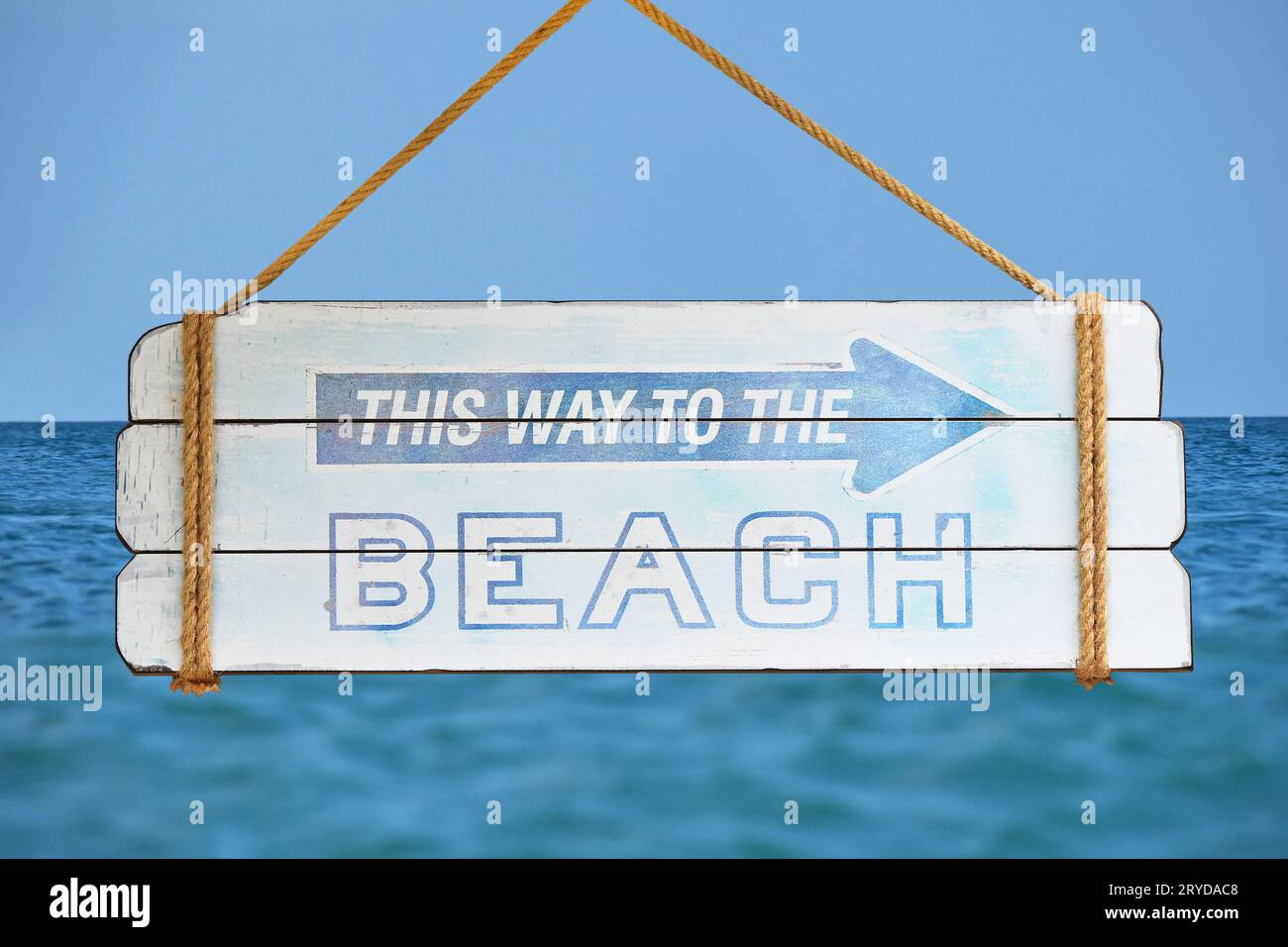 Way to beach sign over blue sky and sea Stock Photo