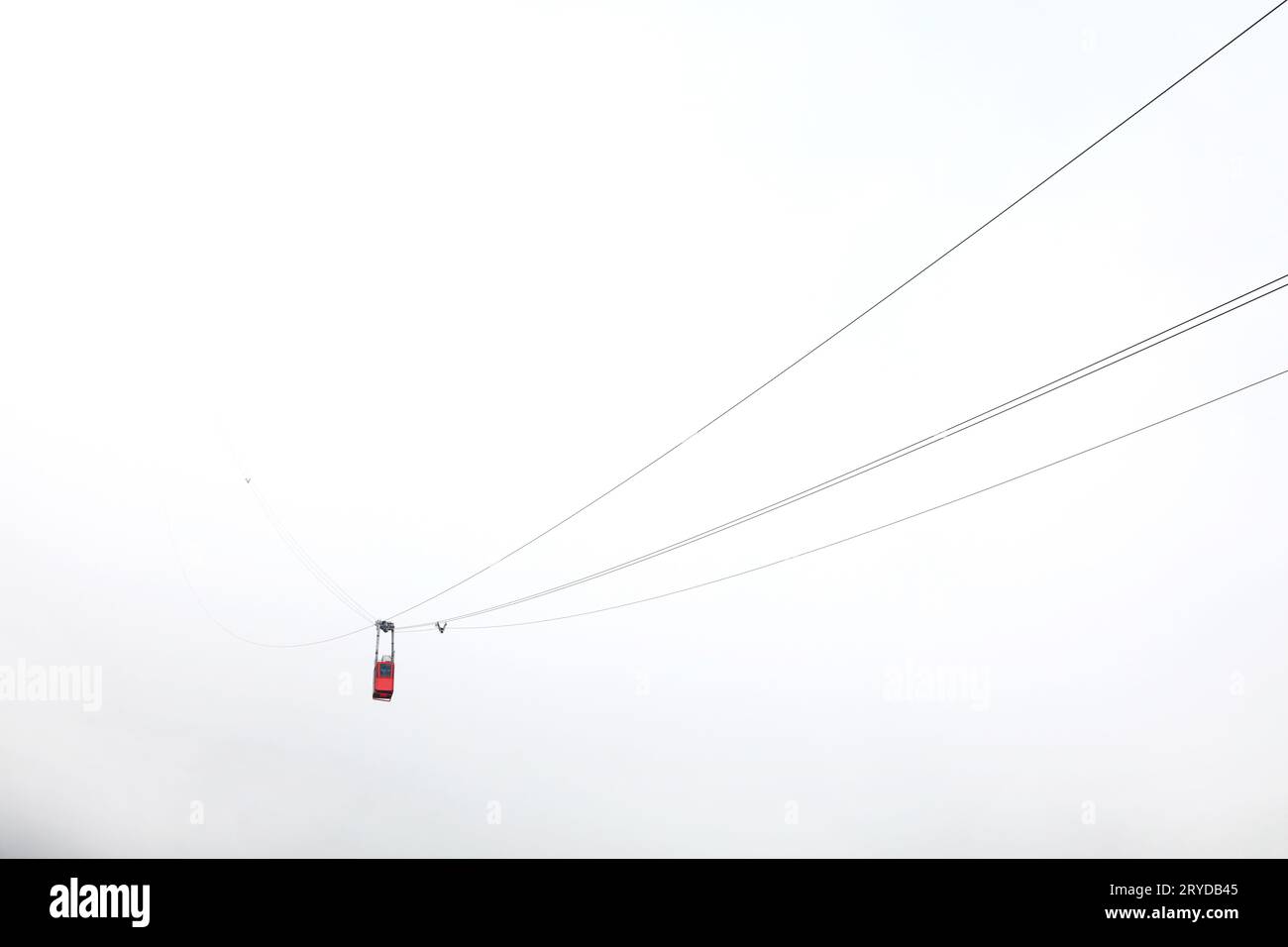 Red mountain cableway car in clouds and fog Stock Photo